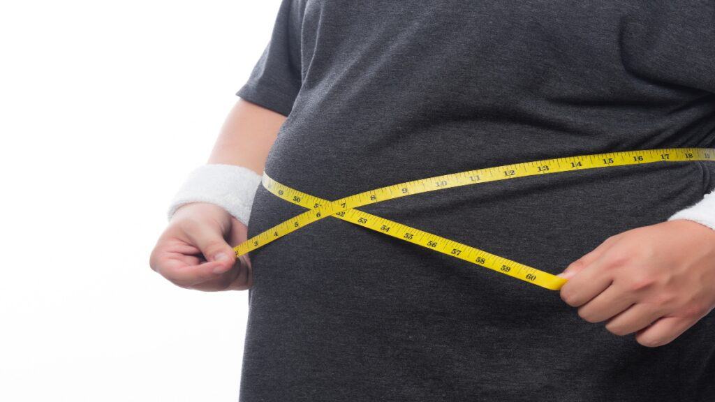 A 35 BMI man measuring his overweight belly
