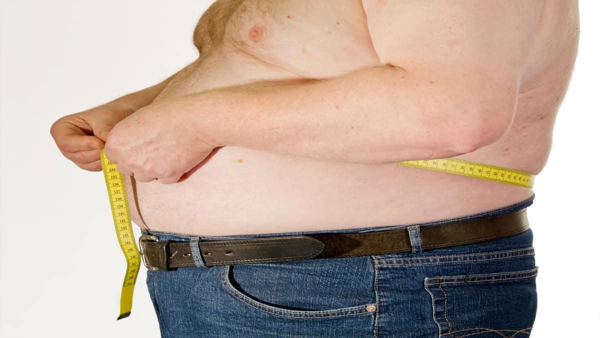 A 51 BMI man measuring his belly
