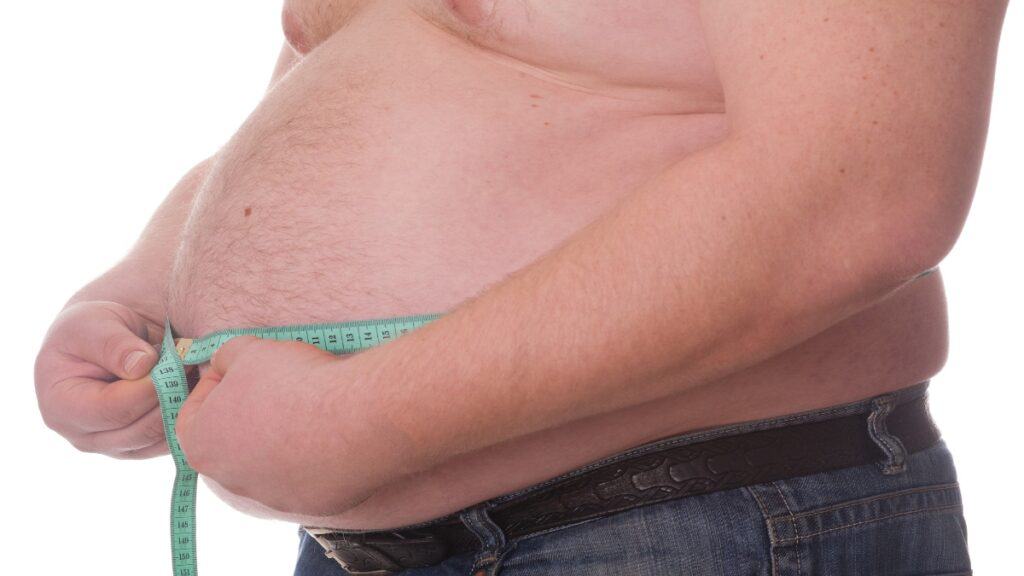 A 53 BMI man measuring his waist
