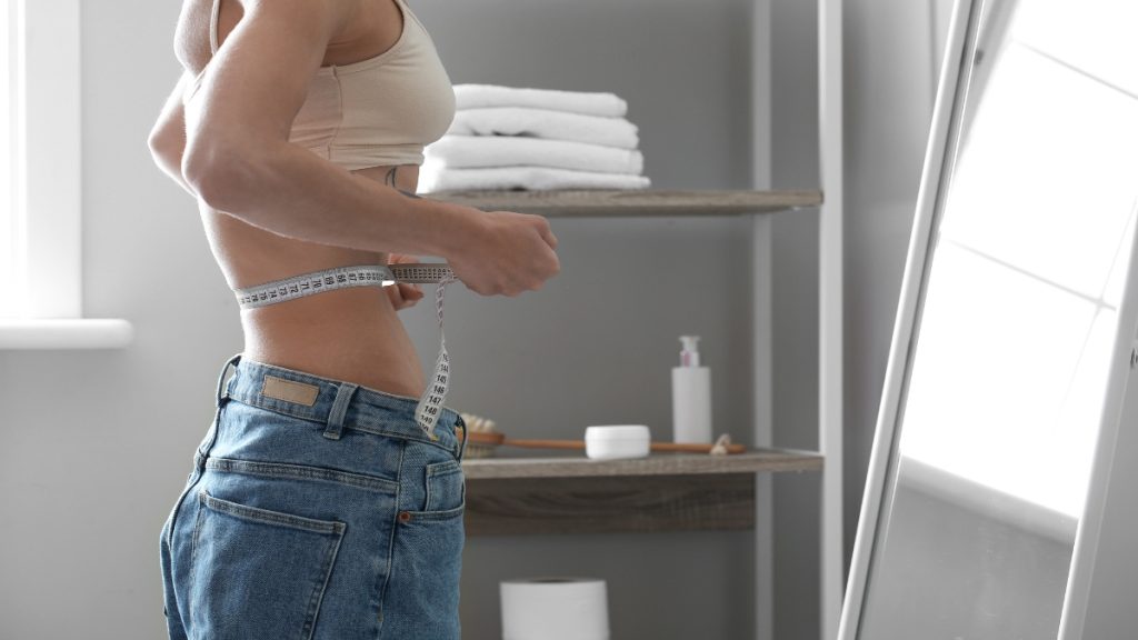 A BMI 10 woman measuring herself