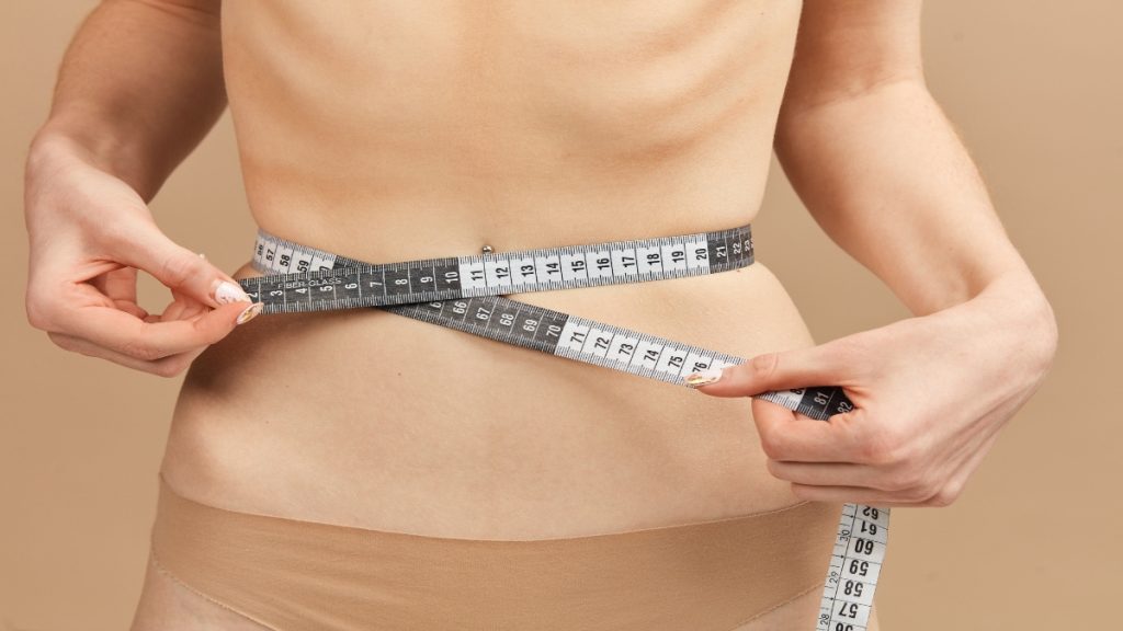 A BMI 7 woman measuring her stomach