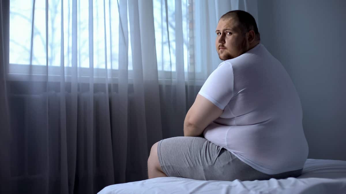 A man with a BMI of 57 sat on his bed