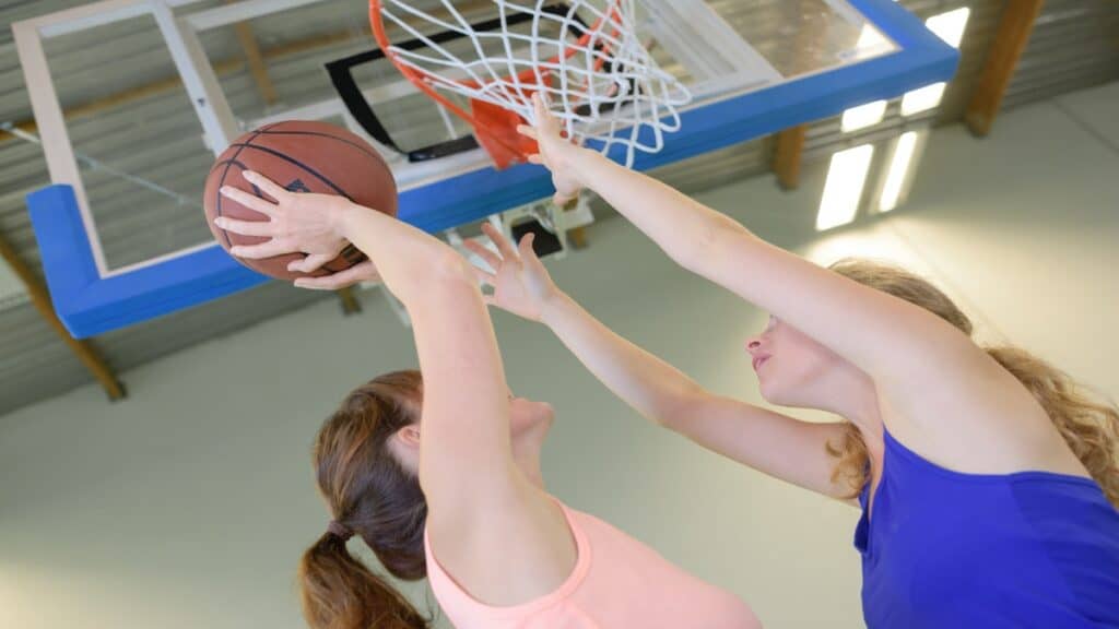 A 6’10 female basketball player reaching for the hoop