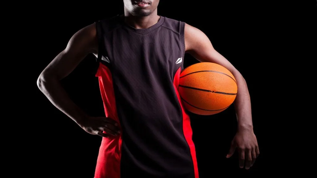 A 6 foot 2 basketball player holding a ball under his arm